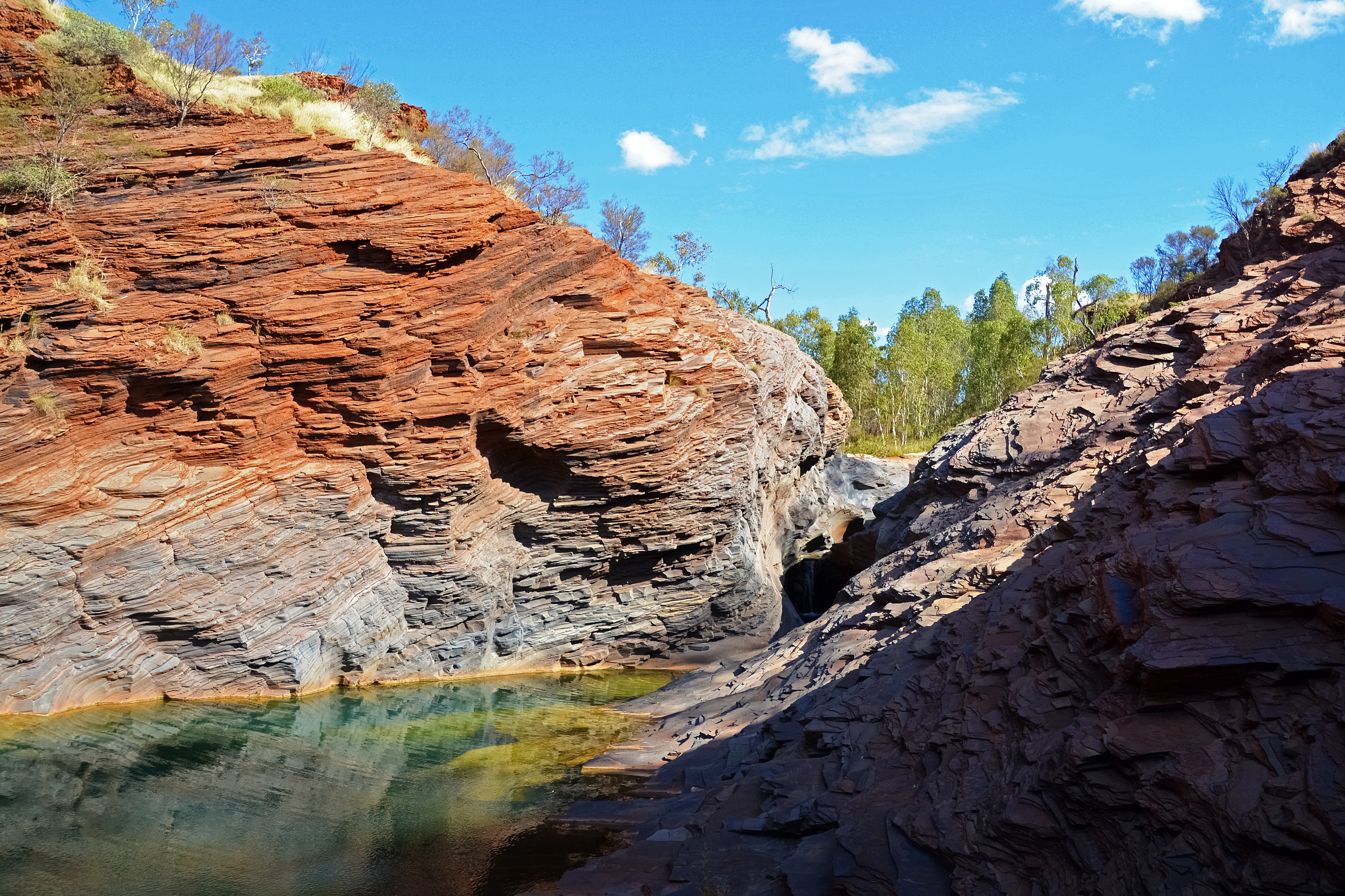 brown rock formation near green trees and body of water during daytime